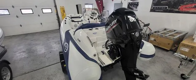 Slide: The Image of 2024 Walker Bay Venture 14 boat with Mercury 60 engine in a garage setting. - 2