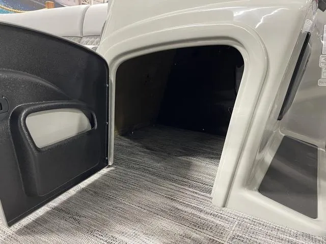 Slide: The Image of 2025 Ranger 220FC boat storage compartment with open door, showcasing interior space and carpeted flooring. - 13