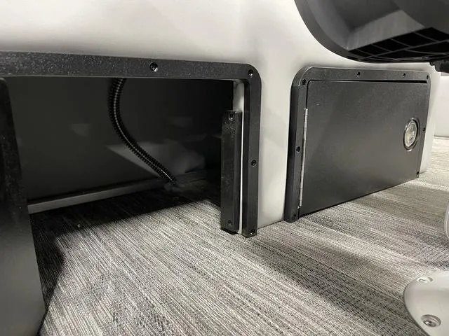 Slide: The Image of Interior view of a 2025 Ranger 220FC, featuring storage compartments and wiring on a carpeted floor. - 27