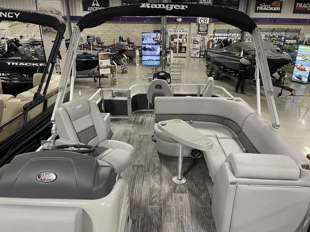Slide: The Image of 2025 Ranger 220FC pontoon boat interior with seating and table, displayed in a showroom. - 9