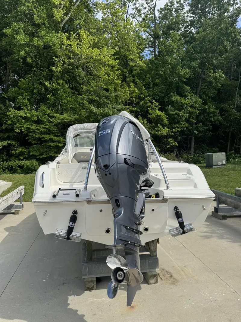 Slide: The Image of 2025 Key West 203 DFS boat with outboard motor, parked on a concrete surface, surrounded by trees. - 3