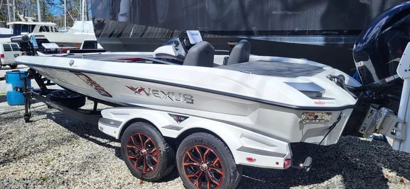 Slide: The Image of 2021 Vexus VX20 boat with sleek design and red-accented wheels, parked on gravel. - 3