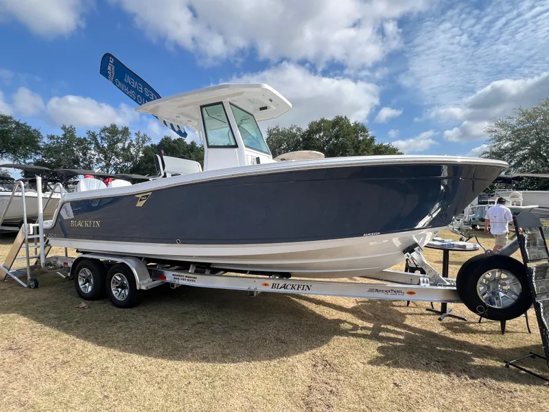 The Image of 2025 Blackfin 252 CC boat on trailer, displayed outdoors under a partly cloudy sky. - 1