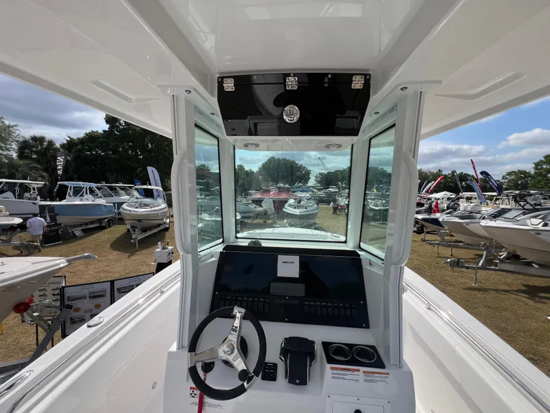 Slide: The Image of 2025 Blackfin 252 CC boat interior at a boat show, showcasing steering and control panel. - 18