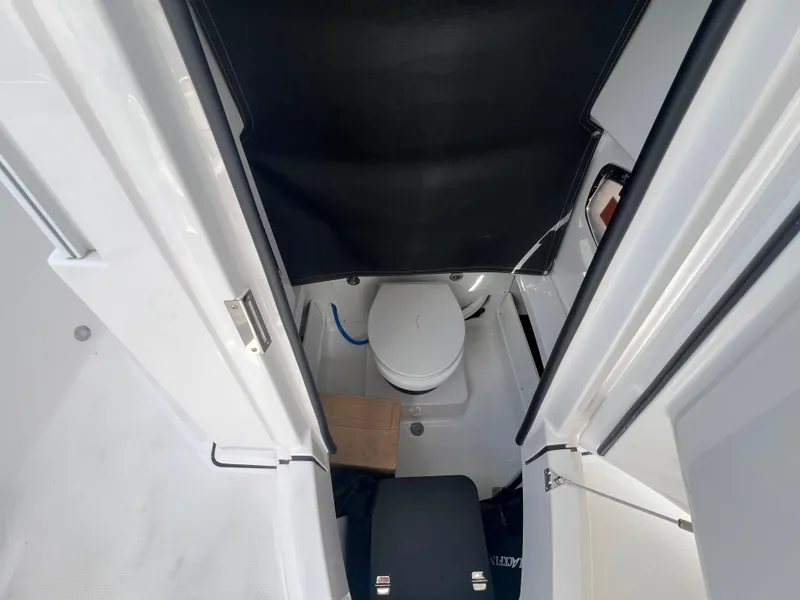 Slide: The Image of 2025 Blackfin 252 CC boat interior with compact marine toilet and storage area. - 23
