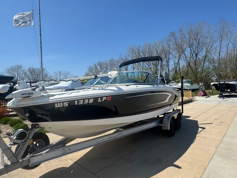 Slide: The Image of 2020 Chaparral 21 SSi Ski & Fish OB boat on trailer, parked outdoors under clear sky. - 2