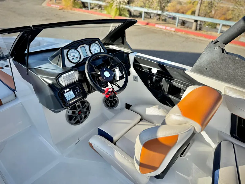 Slide: The Image of 2021 Axis T22 boat interior with steering wheel, dashboard, and orange-accented seats. - 29
