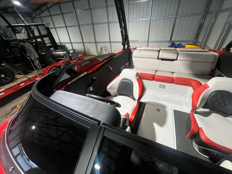 Slide: The Image of 2022 Crownline 240 SS LPX boat interior with red and gray seating in a storage facility. - 12