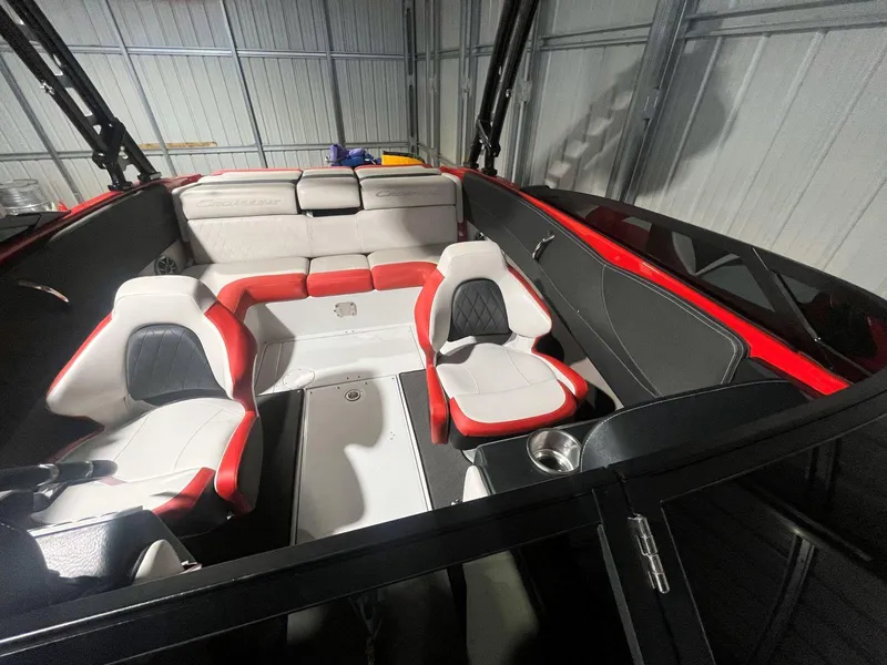 Slide: The Image of 2022 Crownline 240 SS LPX boat interior with red and white seating in a storage facility. - 13