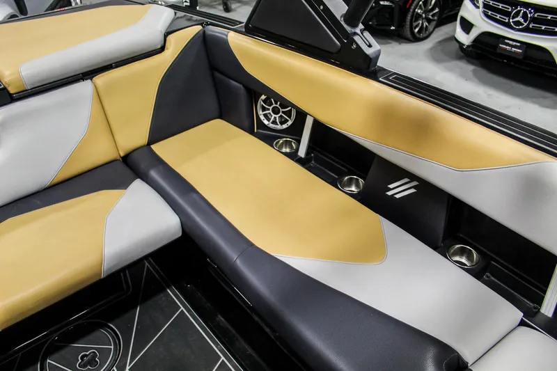 Slide: The Image of 2021 ATX Surf Boats 22 Type-S interior with tan and gray seating, cup holders, and speaker. - 26