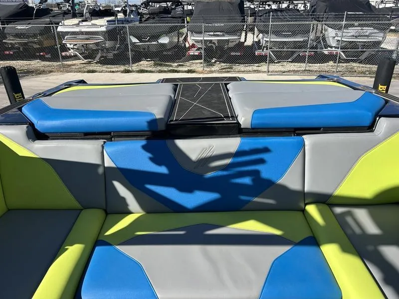 Slide: The Image of 2022 ATX Surf Boats 22 Type-S interior with blue and green seating, docked at marina. - 2