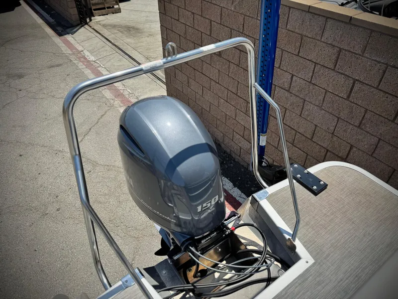 Slide: The Image of 2023 Bennington SX 21 boat with a 150 HP outboard motor, parked on concrete. - 18