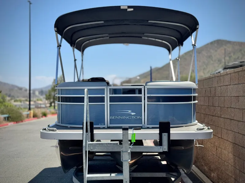 Slide: The Image of 2023 Bennington SX 21 pontoon boat parked, featuring a sleek design and canopy. - 2