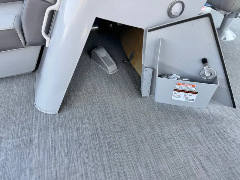 Slide: The Image of 2023 Bennington SX 21 boat storage compartment with open hatch on gray flooring. - 27