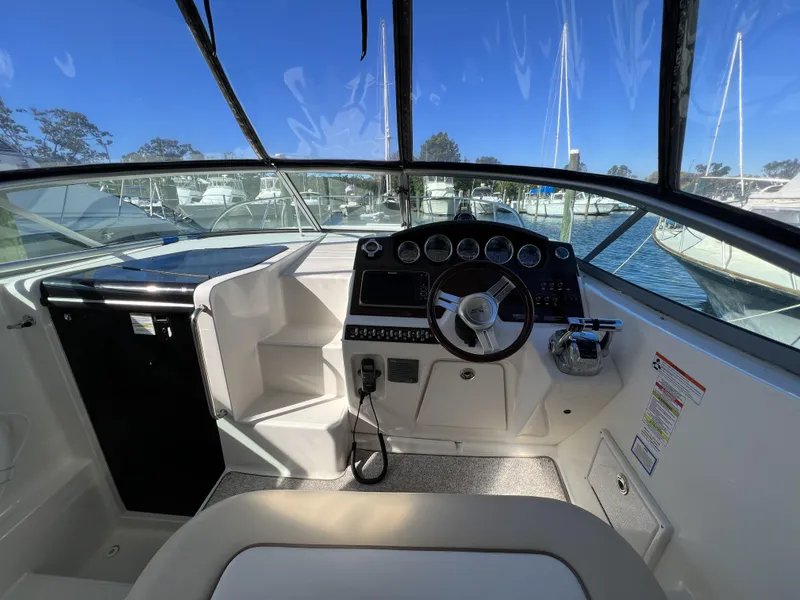 Slide: The Image of Interior of 2012 Sea Ray 310 Sundancer boat with cushioned seating and covered controls. - 13