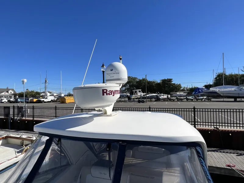 Slide: The Image of Bow view of 2012 Sea Ray 310 Sundancer in a marina with sailboats. - 17