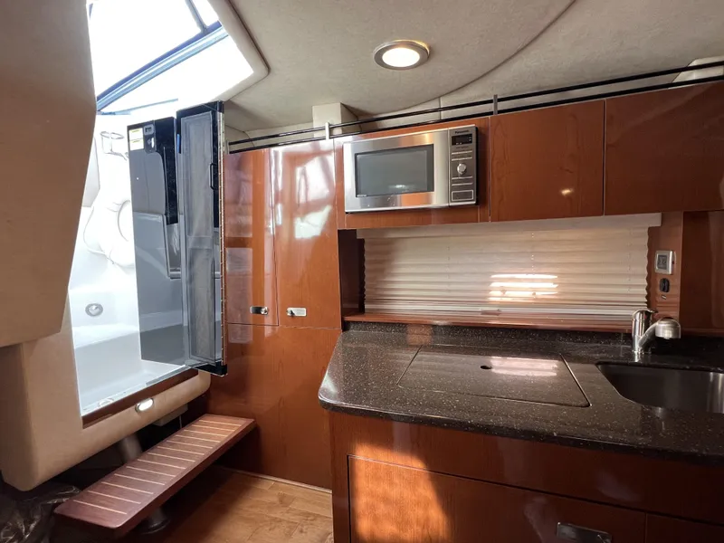 Slide: The Image of Interior of 2012 Sea Ray 310 Sundancer with beige seating and wooden cabinetry. - 22