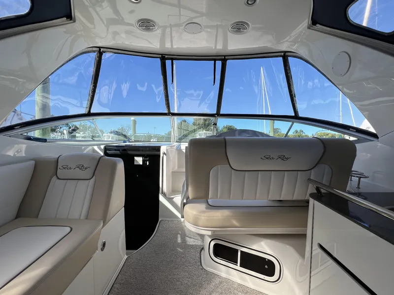 Slide: The Image of Interior of 2012 Sea Ray 310 Sundancer boat with beige seating and large windows. - 8
