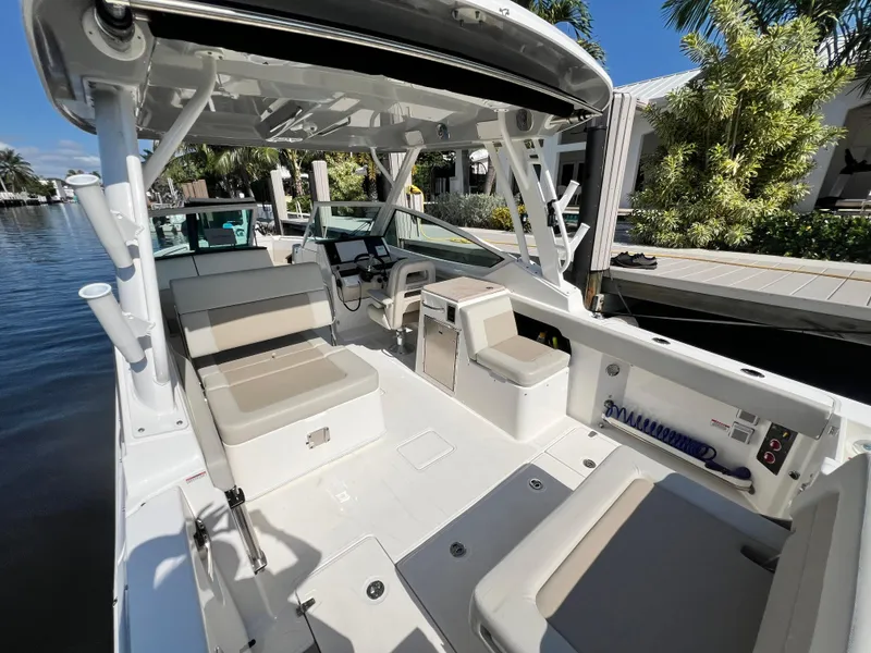 Slide: The Image of 2023 Boston Whaler 280 Vantage boat interior with seating and helm, docked by the water. - 11