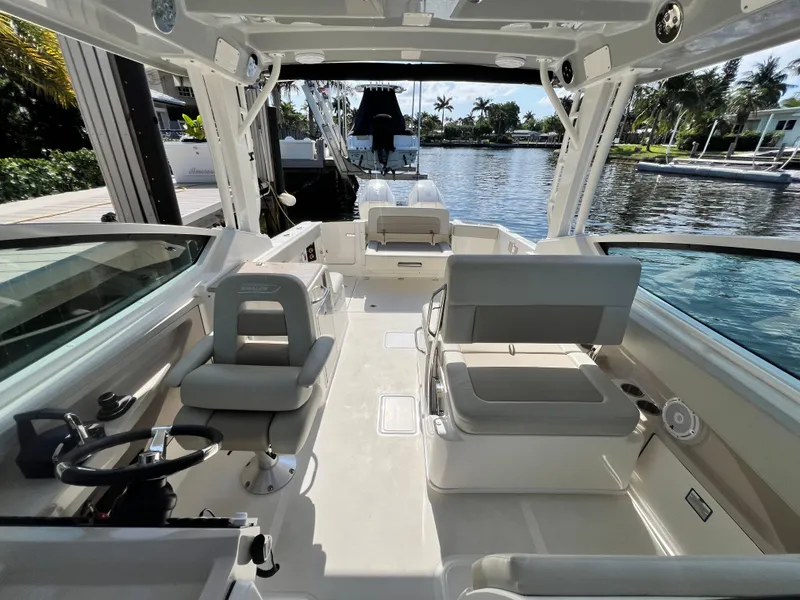 Slide: The Image of 2023 Boston Whaler 280 Vantage boat interior with seating and steering, docked by the water. - 13