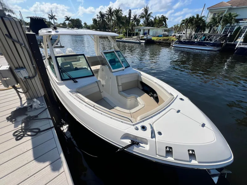 Slide: The Image of 2023 Boston Whaler 280 Vantage boat docked on a sunny day, surrounded by water and palm trees. - 6