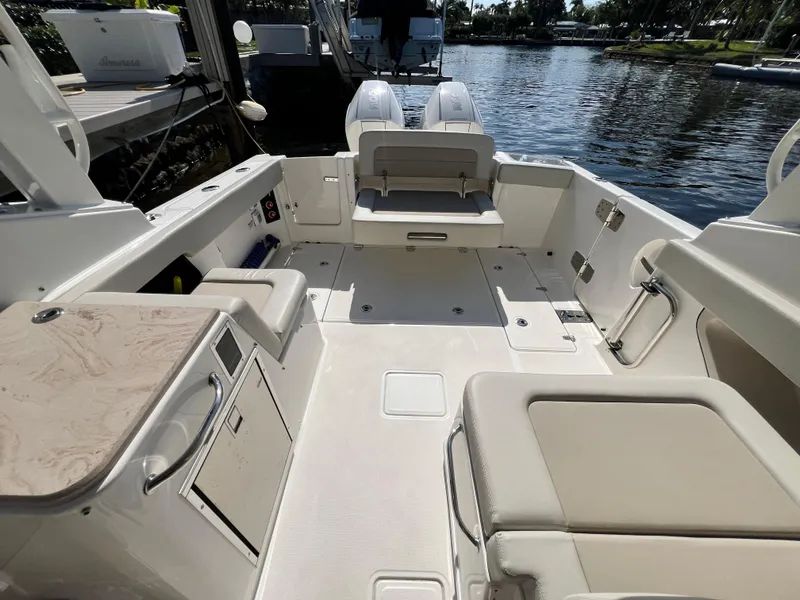 Slide: The Image of 2023 Boston Whaler 280 Vantage boat interior with seating and storage, docked by the water. - 9