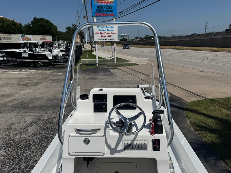 Slide: The Image of 2019 Shallow Sport 21 Sport boat console with steering wheel, parked near a road. - 5