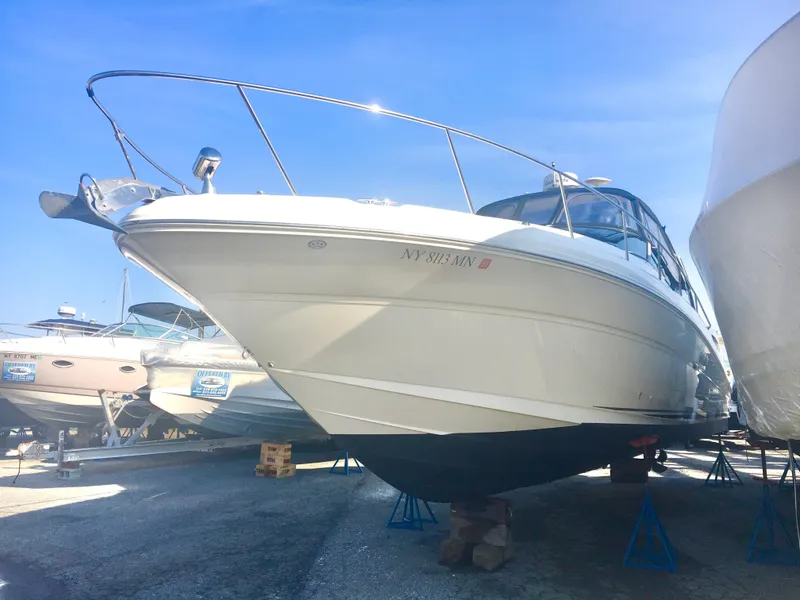 Slide: The Image of 2004 Sea Ray 340 Sundancer boat on stands in a marina under clear blue sky. - 2