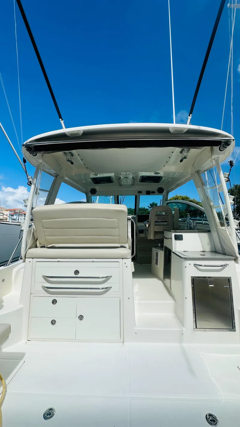 Slide: The Image of 2018 Boston Whaler 345 Conquest boat interior with seating and storage, under a clear blue sky. - 6