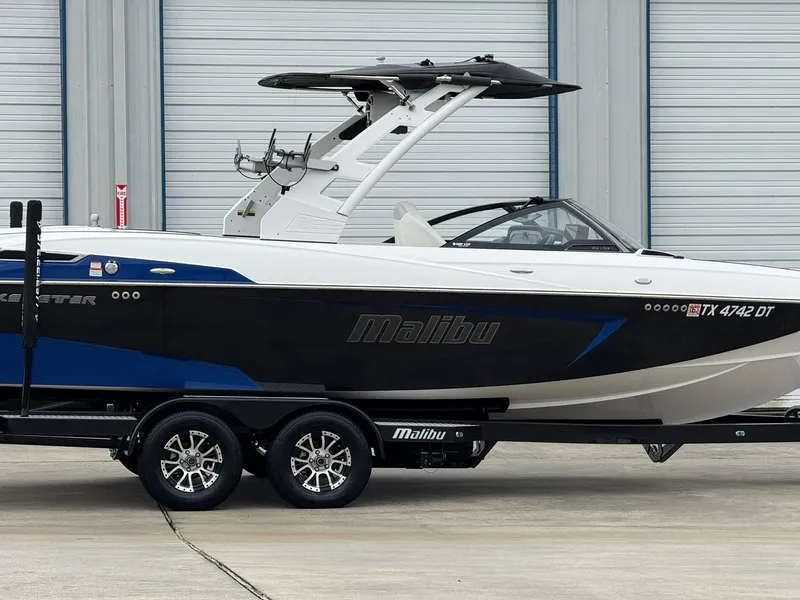 Slide: The Image of 2017 Malibu Wakesetter 23 LSV boat on trailer, parked near industrial building. - 3