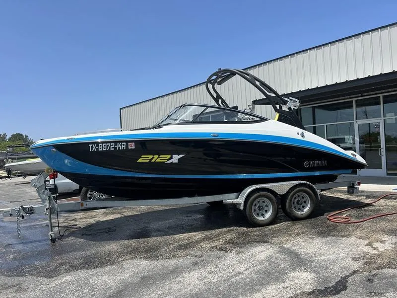 Slide: The Image of 2022 Yamaha Boats 212XE on trailer outside a building. - 0