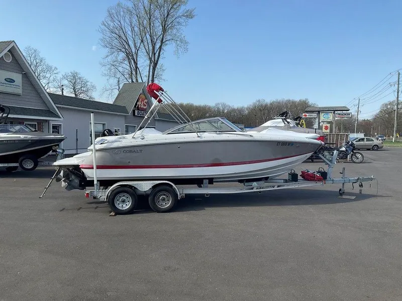Slide: The Image of 2013 Cobalt 210 boat on trailer in parking lot, clear sky background. - 0