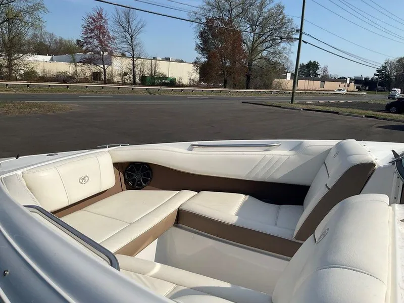 Slide: The Image of 2013 Cobalt 210 boat interior with white seating and brown accents, parked outdoors. - 14