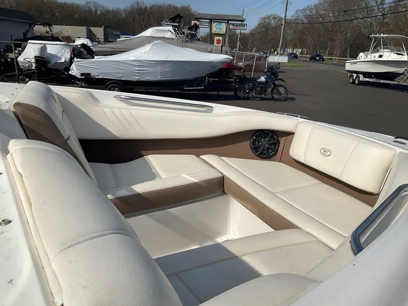 Slide: The Image of 2013 Cobalt 210 boat interior with white and brown seating, parked outdoors. - 17