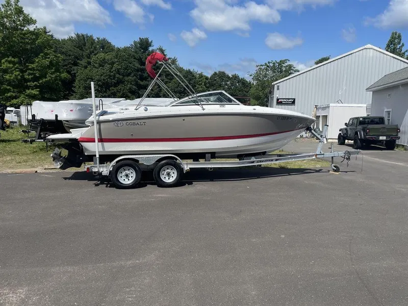 Slide: The Image of 2013 Cobalt 210 boat on trailer, parked outdoors near a white building. - 22