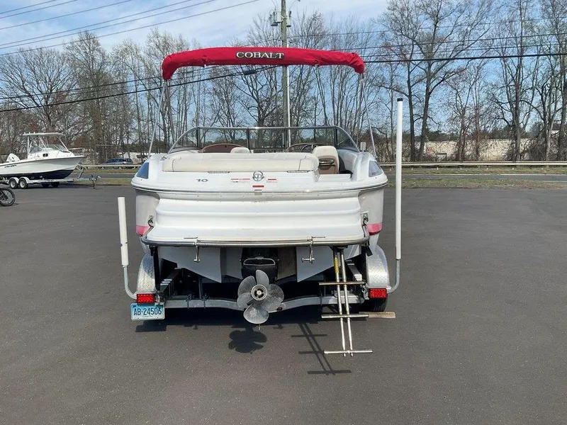 Slide: The Image of 2013 Cobalt 210 boat with red canopy, parked on a trailer, rear view. - 23