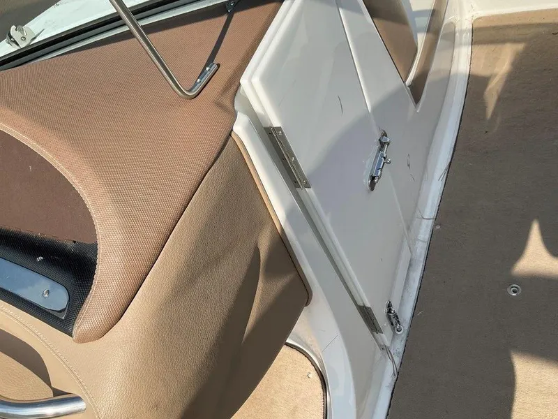 Slide: The Image of Interior of a 2013 Cobalt 210 boat, featuring beige upholstery and a white storage compartment. - 9