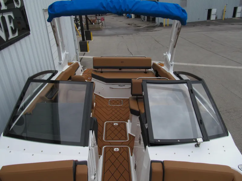 Slide: The Image of 2025 Cobalt R6 boat interior with brown seating and blue canopy, docked at marina. - 19