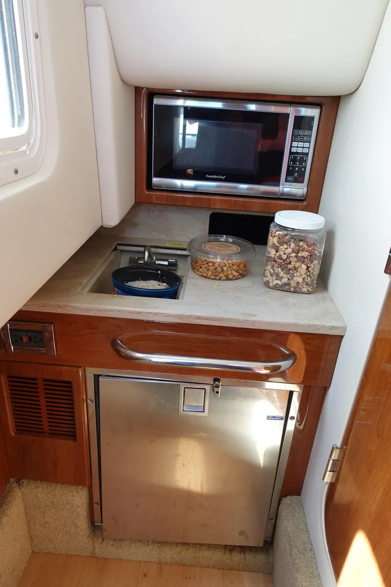 Slide: The Image of 2015 Formula 350 Crossover Bowrider kitchenette with microwave, sink, and mini fridge. - 22