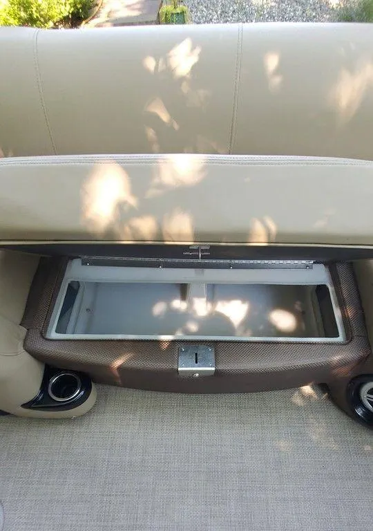 Slide: The Image of 2017 Regency 220 DL3 boat seat storage compartment, open with beige upholstery. - 27