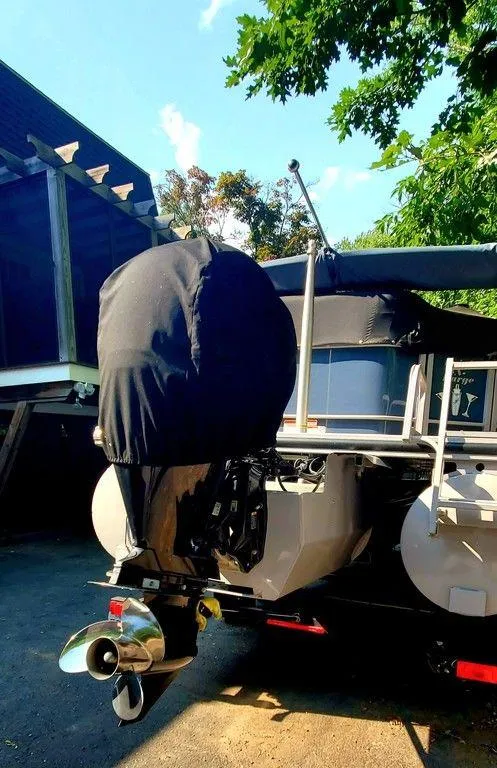 Slide: The Image of 2017 Regency 220 DL3 boat with covered outboard motor, parked under trees. - 3