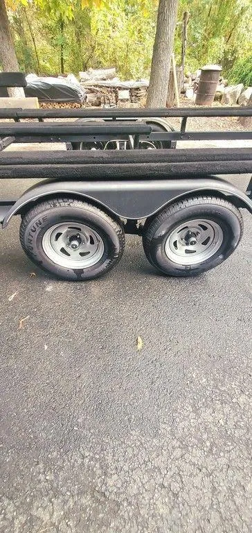 Slide: The Image of Trailer wheels on a 2017 Regency 220 DL3, parked on asphalt with trees in the background. - 35