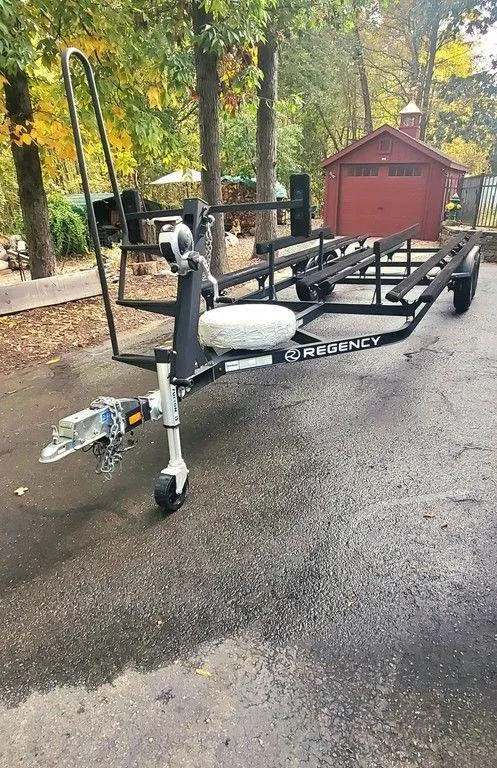 Slide: The Image of 2017 Regency 220 DL3 boat trailer on driveway, surrounded by trees and a red shed. - 36