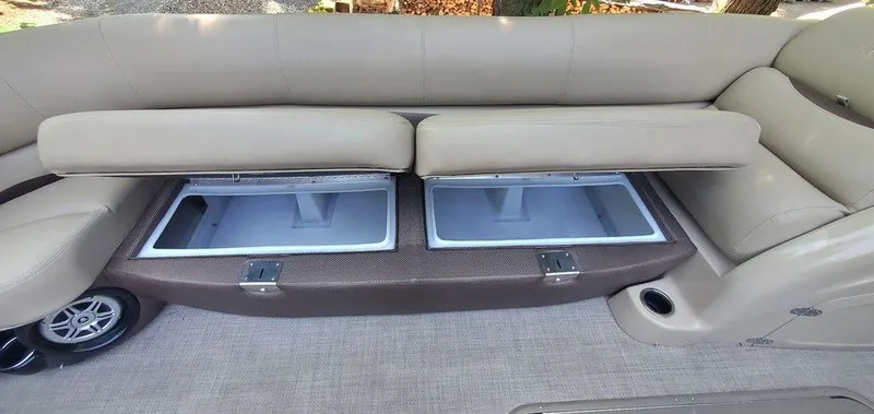 Slide: The Image of 2017 Regency 220 DL3 boat interior with open storage compartments under beige seating. - 38