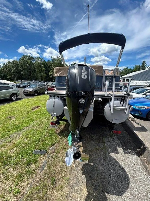 Slide: The Image of 2017 Regency 220 DL3 pontoon boat with outboard motor, parked outdoors under a blue sky. - 42