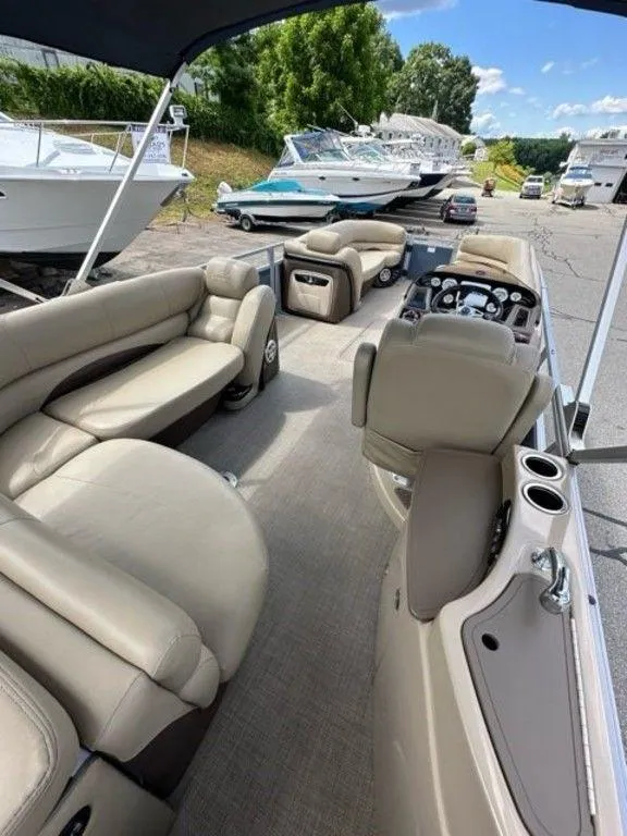 Slide: The Image of 2017 Regency 220 DL3 pontoon boat with beige seating and modern dashboard, docked outdoors. - 8