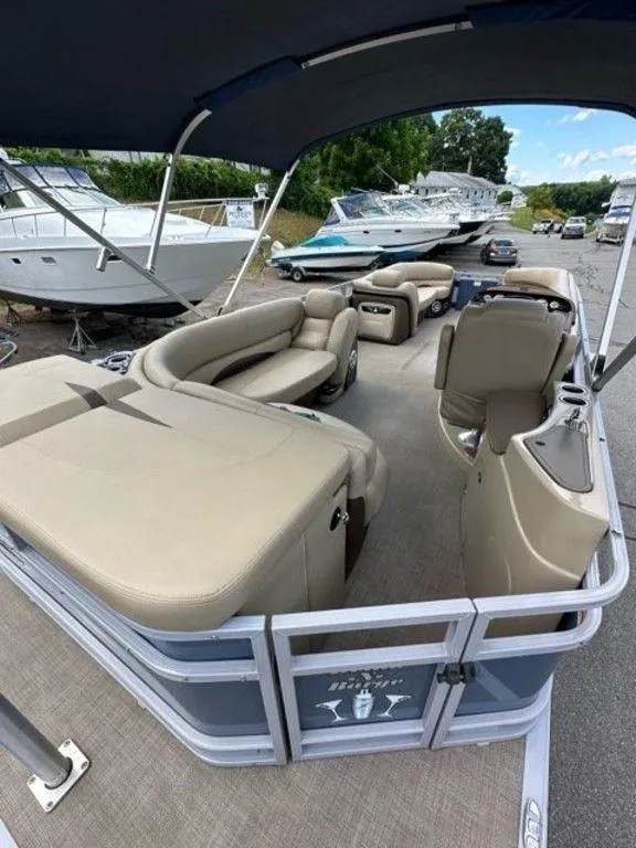 Slide: The Image of 2017 Regency 220 DL3 pontoon boat with beige seating, docked near other boats. - 9