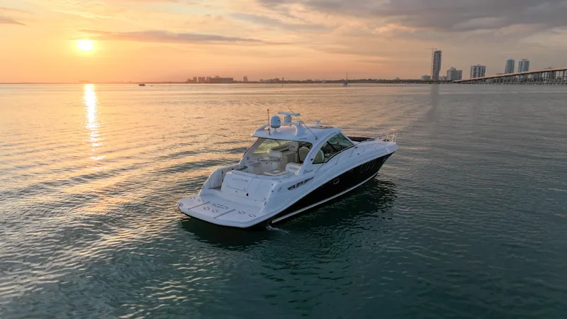 Slide: The Image of 2008 Sea Ray 48 Sundancer yacht cruising at sunset near city skyline. - 10
