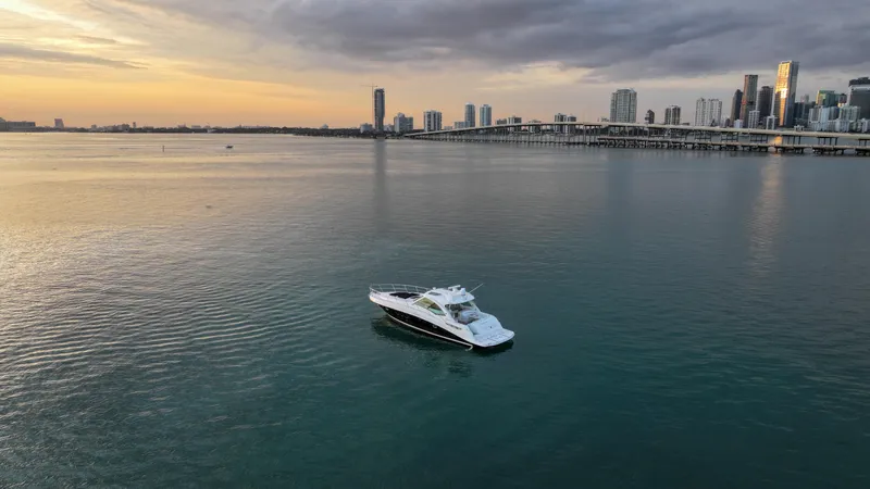 Slide: The Image of 2008 Sea Ray 48 Sundancer yacht on calm water at sunset near city skyline. - 16
