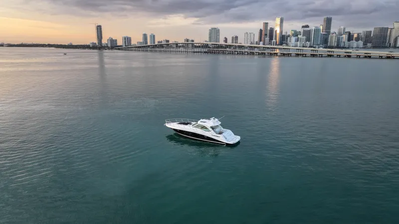 Slide: The Image of 2008 Sea Ray 48 Sundancer yacht on calm water with city skyline backdrop. - 17